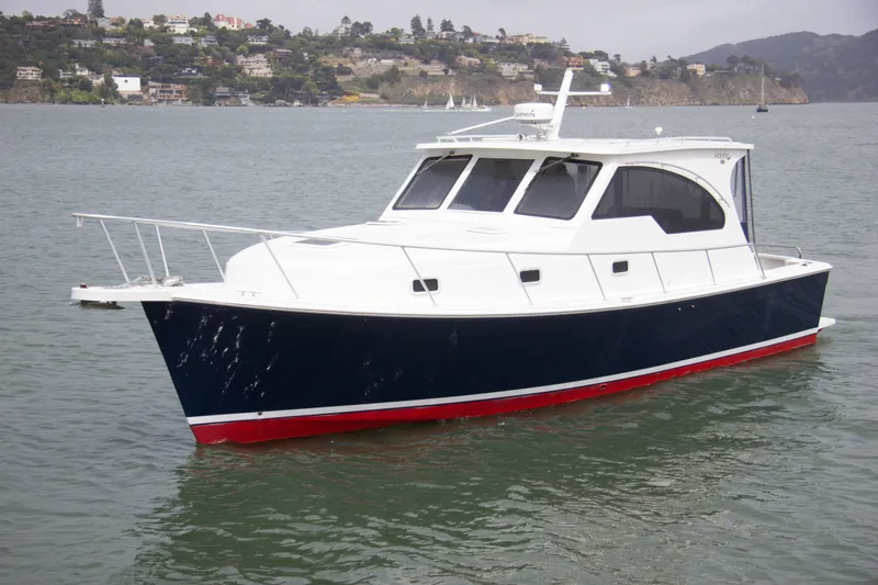 Slide: The Image of 2001 Mainship Pilot 34 Sedan boat on calm water, coastal background. - 2