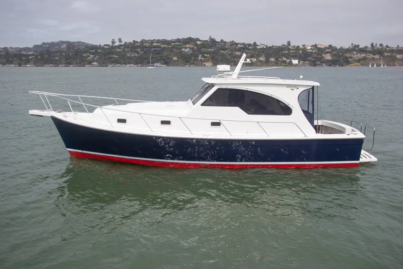 Slide: The Image of 2001 Mainship Pilot 34 Sedan boat on calm water, scenic background. - 3