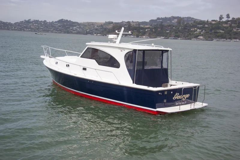 Slide: The Image of 2001 Mainship Pilot 34 Sedan boat on water, scenic background. - 4