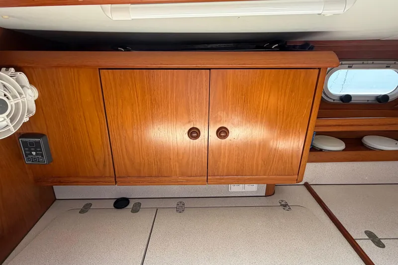 Slide: The Image of Wooden cabinetry inside 1998 Jeanneau Sun Odyssey 45.2 yacht, featuring a fan and porthole. - 57