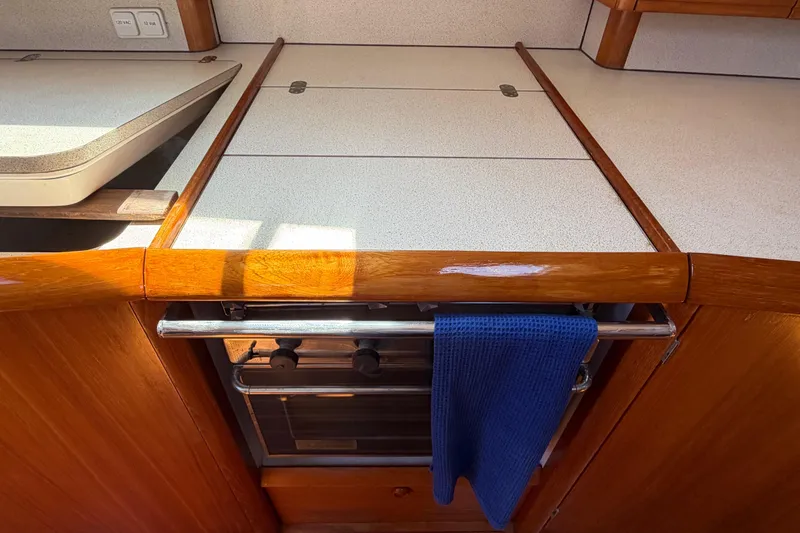 Slide: The Image of Galley kitchen in 1998 Jeanneau Sun Odyssey 45.2 sailboat with wooden cabinetry and oven. - 59