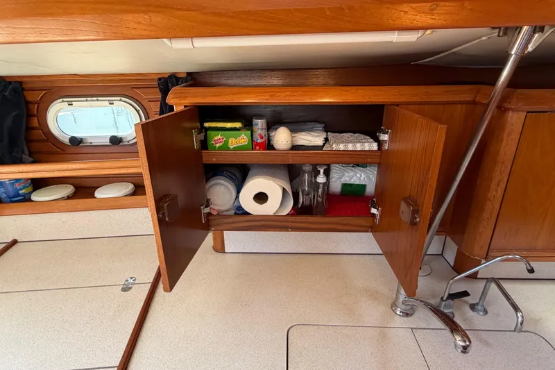 Slide: The Image of Interior of 1998 Jeanneau Sun Odyssey 45.2 yacht with open wooden cabinet and supplies. - 62