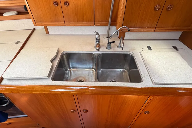 Slide: The Image of Kitchen sink area on a 1998 Jeanneau Sun Odyssey 45.2 yacht, featuring wooden cabinetry. - 67