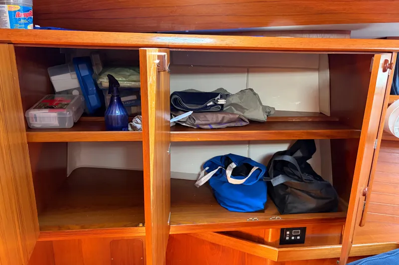Slide: The Image of Wooden cabinet interior on a 1998 Jeanneau Sun Odyssey 45.2 yacht, storing various items. - 70