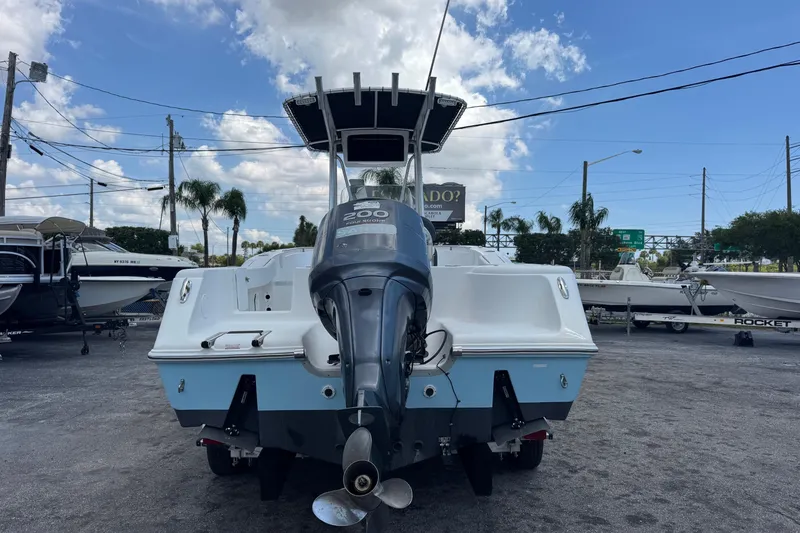 Slide: The Image of 2011 Tidewater 230 CC Adventure boat with outboard motor, parked outdoors under a blue sky. - 4