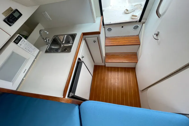 Slide: The Image of 2001 Tiara Yachts 2900 Coronet interior with kitchenette, sink, microwave, and wooden steps. - 44
