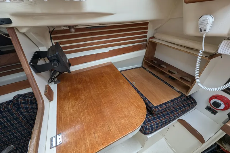 Slide: The Image of 1982 Pearson 323 sailboat interior with wooden table, seating, and communication equipment. - 11