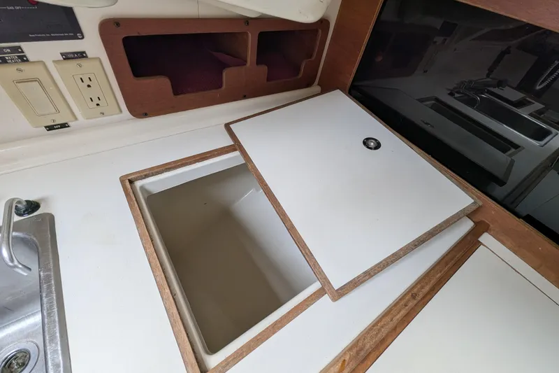 Slide: The Image of Interior of a 1982 Pearson 323 sailboat showing a storage compartment and sink area. - 15