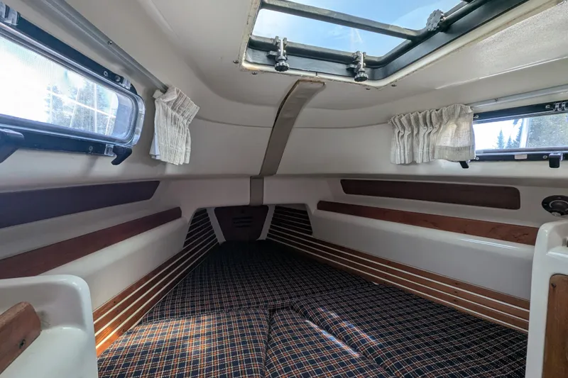 Slide: The Image of Interior cabin of a 1982 Pearson 323 sailboat with plaid bedding and wooden accents. - 22