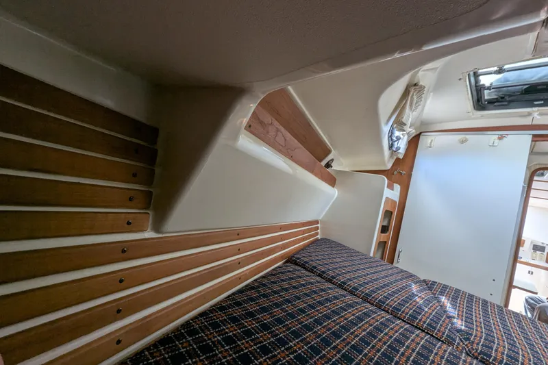 Slide: The Image of Interior cabin of a 1982 Pearson 323 sailboat with wooden accents and plaid bedding. - 23