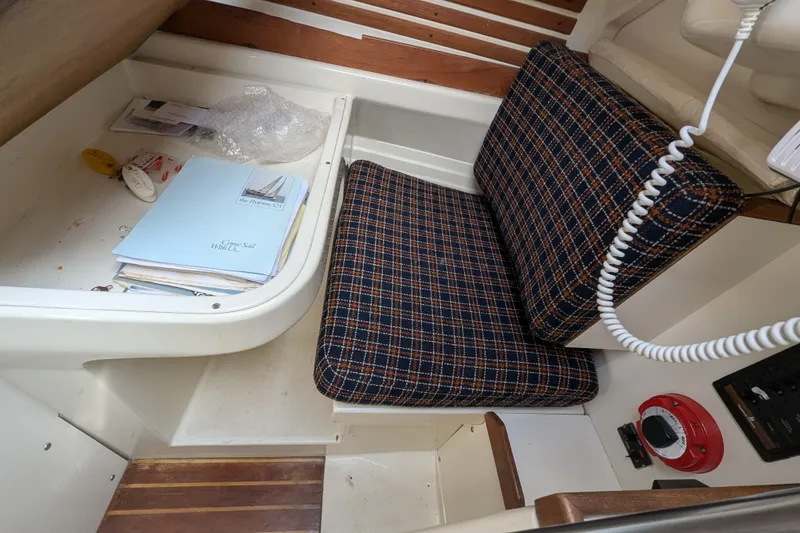 Slide: The Image of Interior of a 1982 Pearson 323 sailboat with plaid seating and navigation materials. - 28