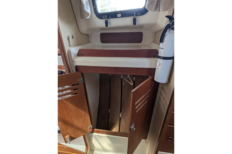 Slide: The Image of Interior of 1982 Pearson 323 sailboat with open wooden cabinet and fire extinguisher. - 32