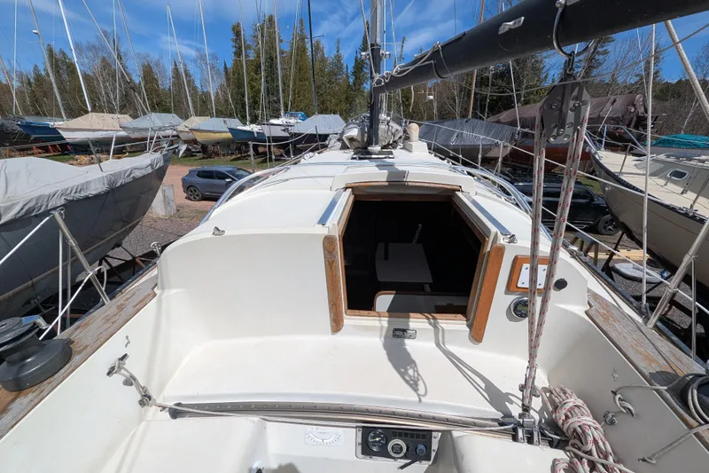 Slide: The Image of 1982 Pearson 323 sailboat on land, surrounded by other boats and trees. - 34
