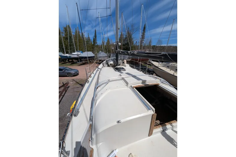 Slide: The Image of 1982 Pearson 323 sailboat on land, surrounded by trees and other boats. - 37