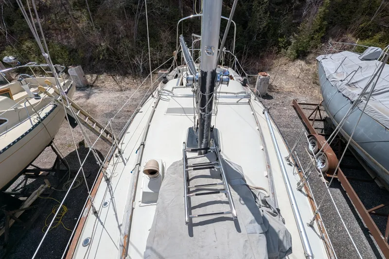 Slide: The Image of 1982 Pearson 323 sailboat on land, mast and deck view, surrounded by trees. - 42