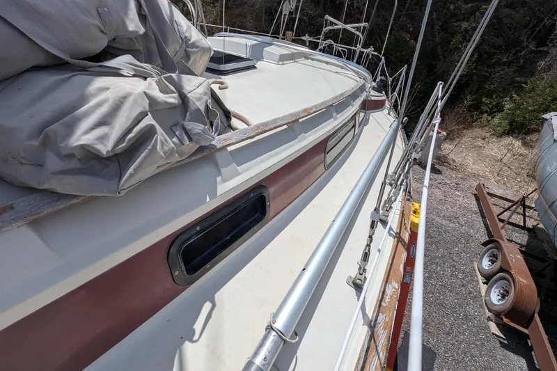 Slide: The Image of 1982 Pearson 323 sailboat deck with railing and covered equipment. - 51
