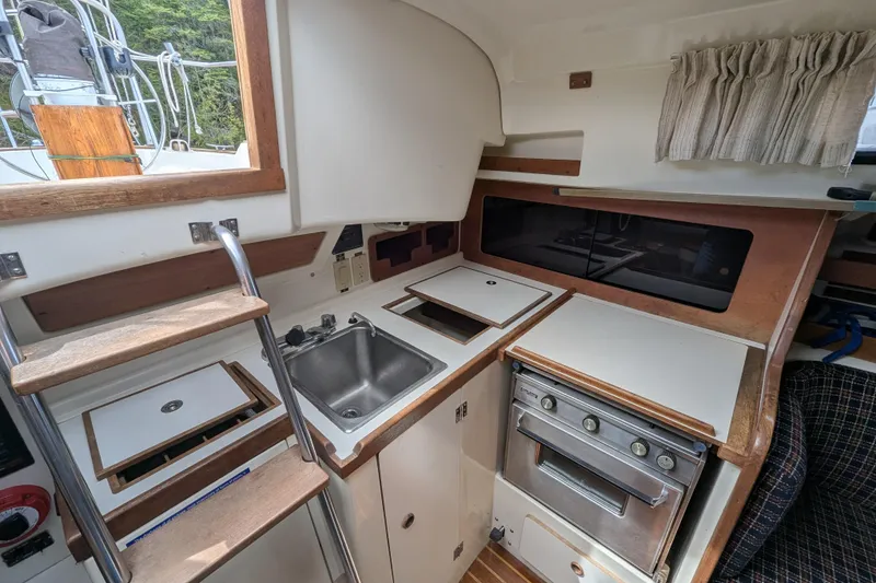 Slide: The Image of Interior of a 1982 Pearson 323 sailboat galley with sink, stove, and wooden cabinetry. - 6