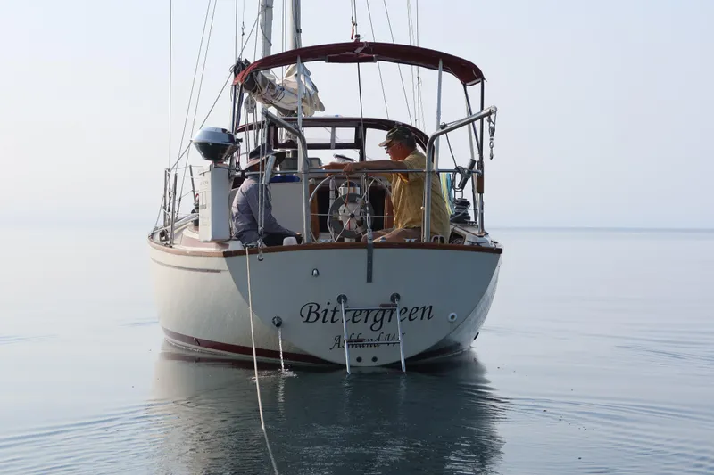 Slide: The Image of 1982 Pearson 323 sailboat "Bittergreen" on calm water with two people aboard. - 62