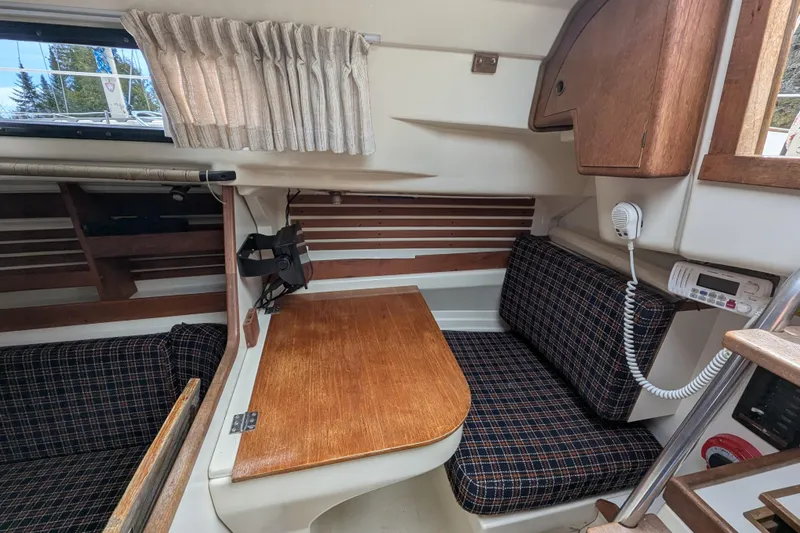 Slide: The Image of 1982 Pearson 323 sailboat interior with wooden table, plaid seating, and communication equipment. - 8