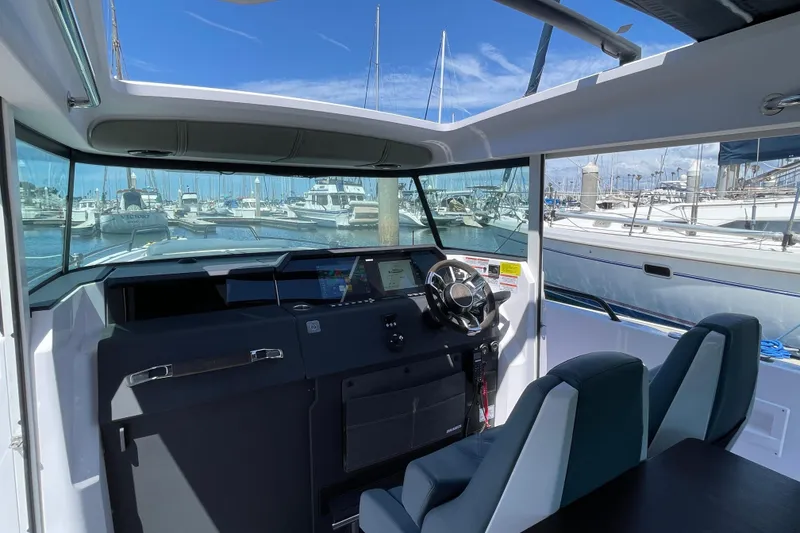 Slide: The Image of Interior view of 2023 Axopar 37 XC Cross Cabin at marina, showcasing helm and seating. - 20