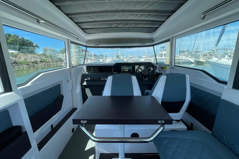 Slide: The Image of Interior of 2023 Axopar 37 XC Cross Cabin with seating and helm, docked at marina. - 7