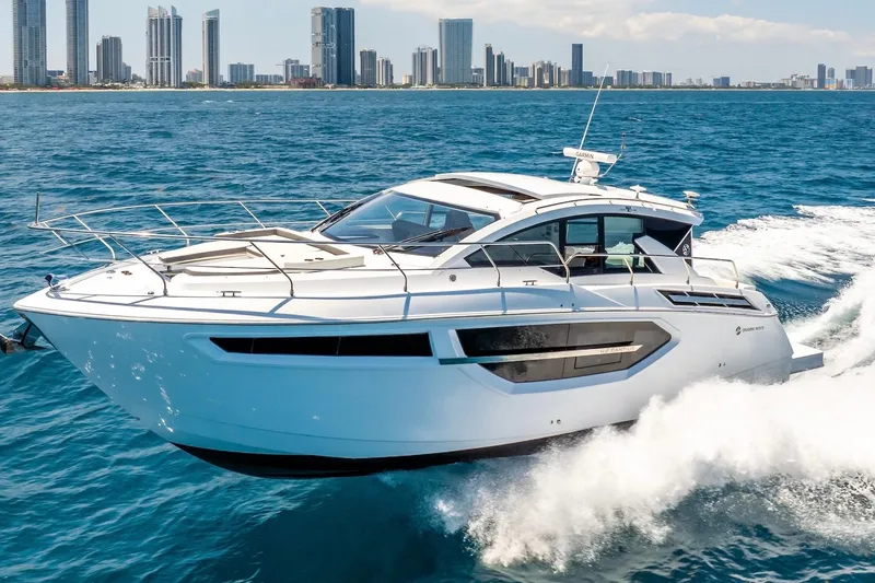 The Image of 2022 Cruisers Yachts 42 Cantius cruising on blue ocean near city skyline. - 0