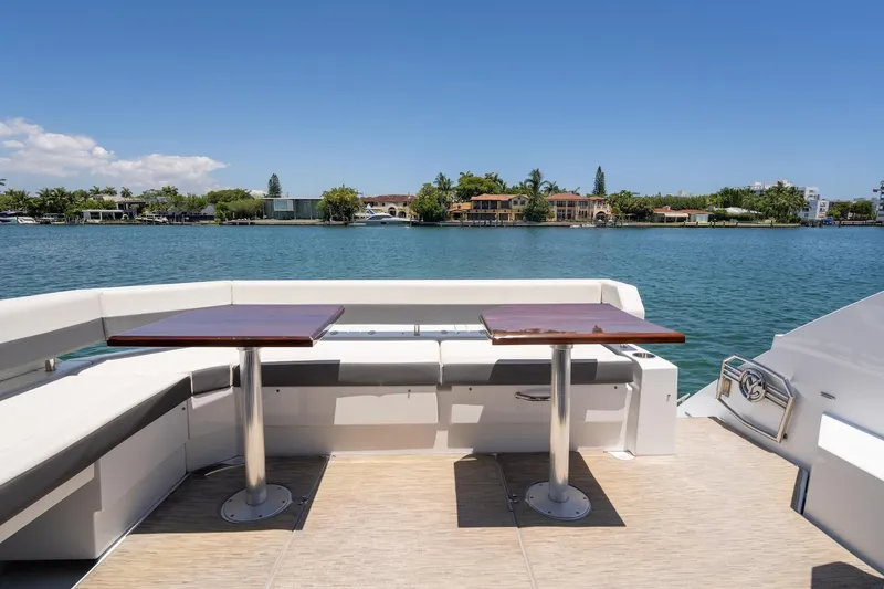 Slide: The Image of 2022 Cruisers Yachts 42 Cantius deck with seating and tables, overlooking serene waterfront. - 25