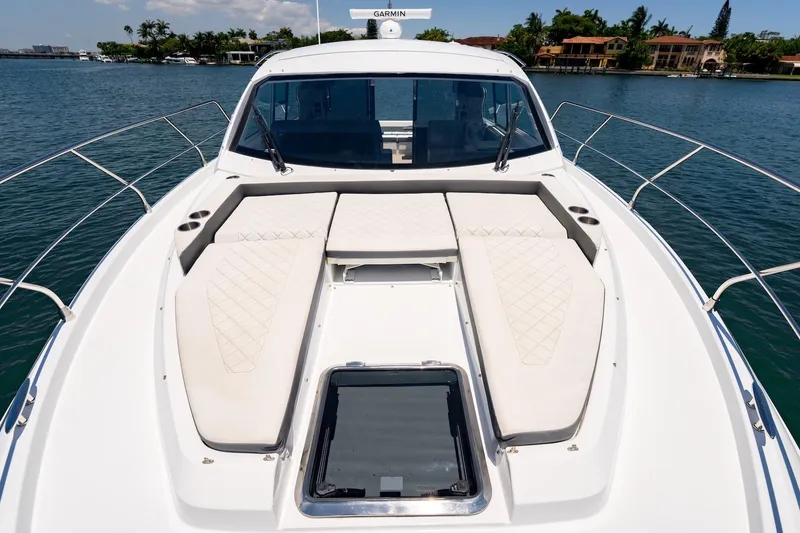 Slide: The Image of 2022 Cruisers Yachts 42 Cantius with sun pads on deck, docked by waterfront homes. - 28