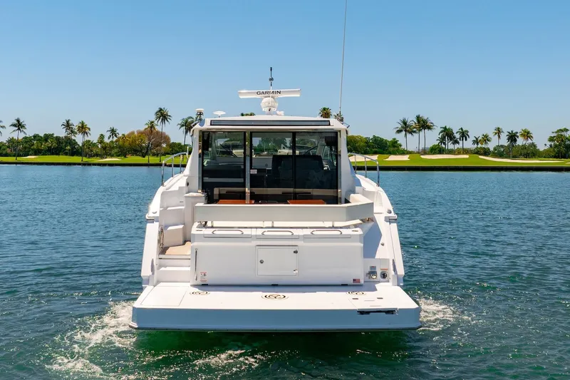Slide: The Image of 2022 Cruisers Yachts 42 Cantius on water, rear view with palm trees in background. - 4