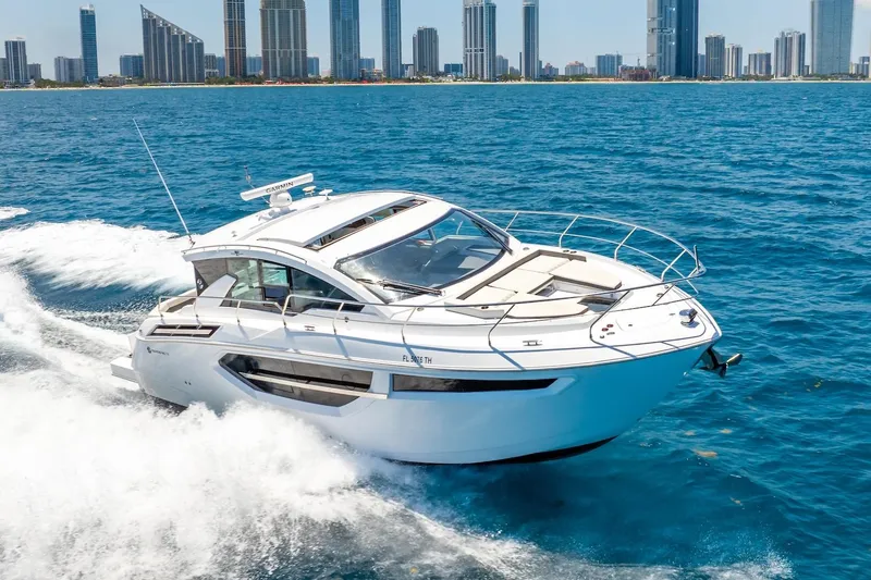 Slide: The Image of 2022 Cruisers Yachts 42 Cantius cruising on blue ocean with city skyline backdrop. - 58