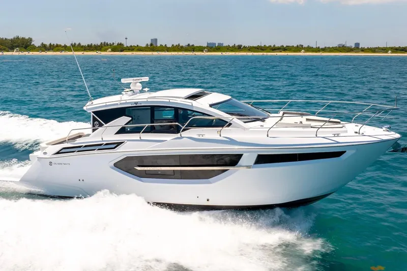 Slide: The Image of 2022 Cruisers Yachts 42 Cantius cruising on blue ocean near sandy shoreline. - 8