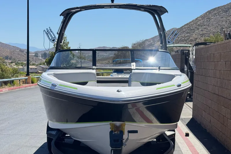 Slide: The Image of 2022 Tahoe 210 Si Limited boat on trailer, parked outdoors with scenic mountain backdrop. - 2