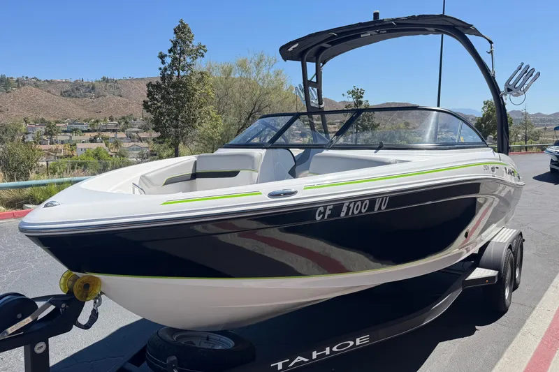 Slide: The Image of 2022 Tahoe 210 Si Limited boat on trailer, parked outdoors with scenic background. - 3