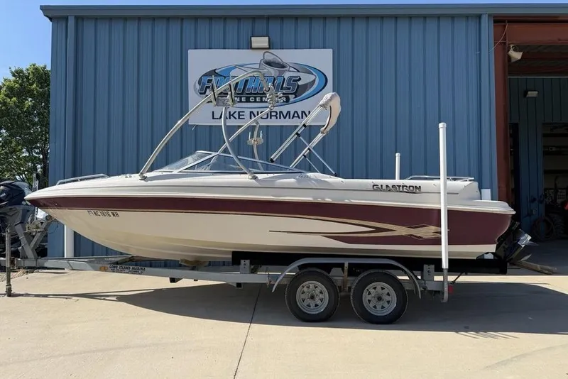 The Image of 1999 Glastron GT 225 boat on trailer outside a marine center. - 1