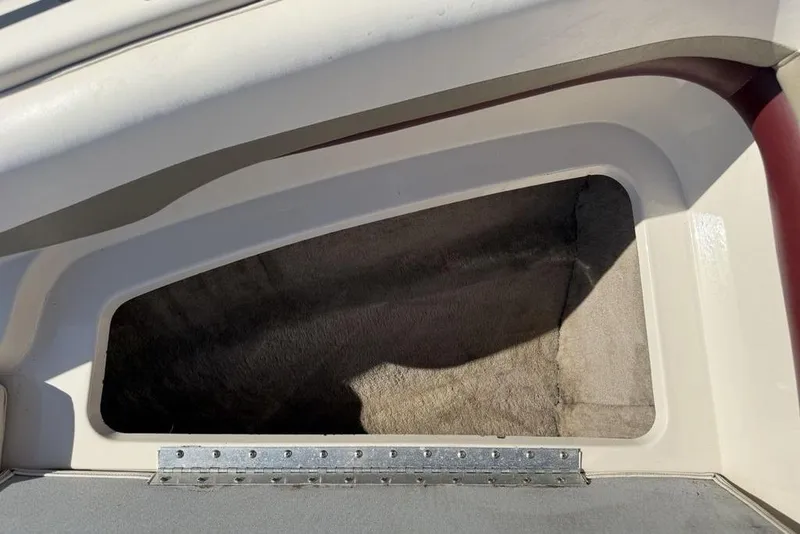 Slide: The Image of Storage compartment of a 1999 Glastron GT 225 boat, featuring a carpeted interior. - 16
