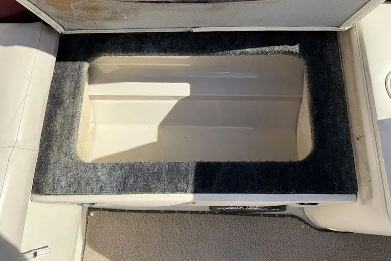 Slide: The Image of Storage compartment in a 1999 Glastron GT 225 boat, featuring a carpeted interior. - 23