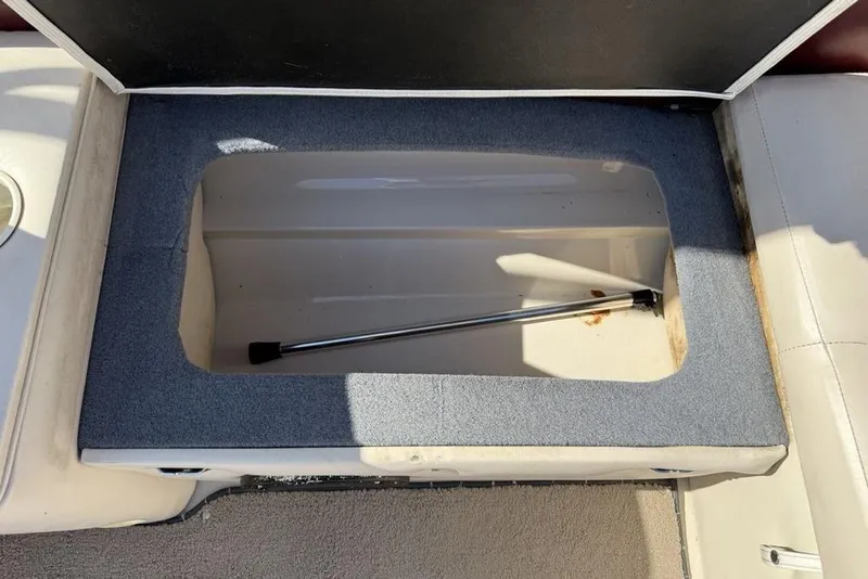 Slide: The Image of Open storage compartment in a 1999 Glastron GT 225 boat, featuring a hydraulic support rod. - 29