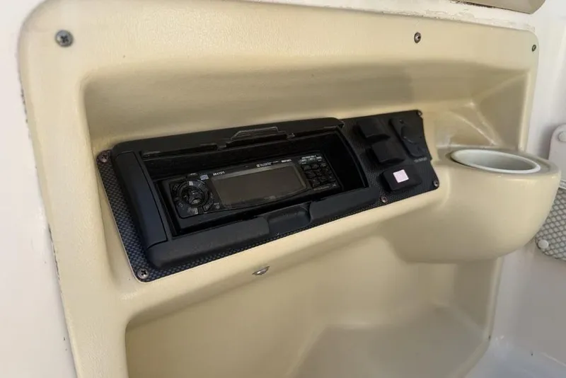Slide: The Image of 1999 Glastron GT 225 boat dashboard with stereo system and cup holder. - 32