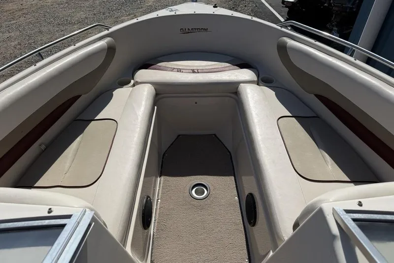Slide: The Image of 1999 Glastron GT 225 boat interior with beige seating and carpeted floor. - 6