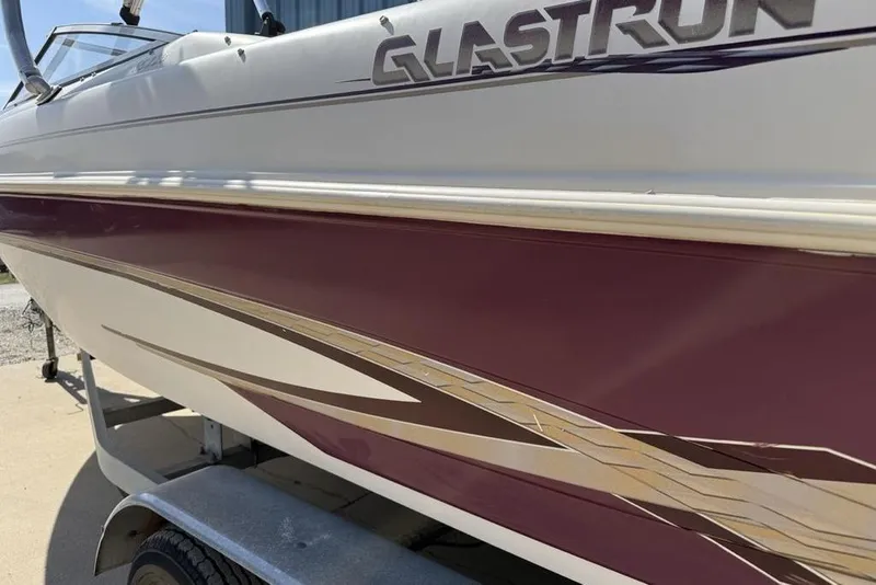 Slide: The Image of 1999 Glastron GT 225 boat with maroon and white detailing on a trailer. - 7