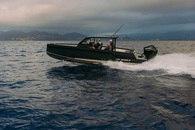 Slide: The Image of 2027 XO DFNDR 8 boat cruising on open water with mountainous backdrop. - 11