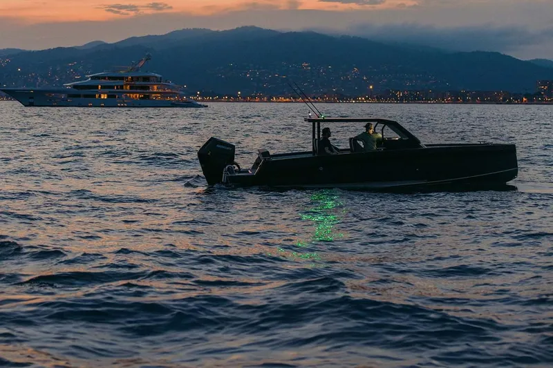 Slide: The Image of 2027 XO DFNDR 8 boat cruising at sunset with city lights in the background. - 8