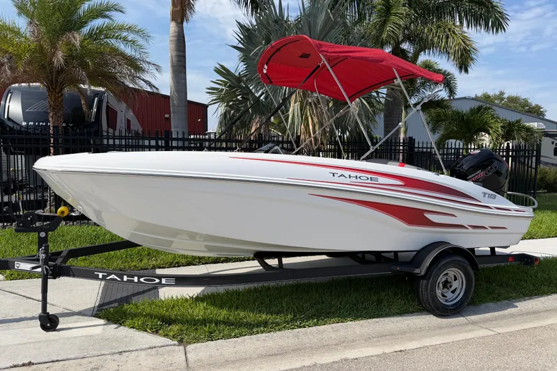The Image of 2023 Tahoe T18 boat with red canopy on trailer, parked near palm trees. - 1