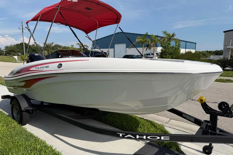 Slide: The Image of 2023 Tahoe T18 boat with red canopy on trailer, parked outdoors. - 17