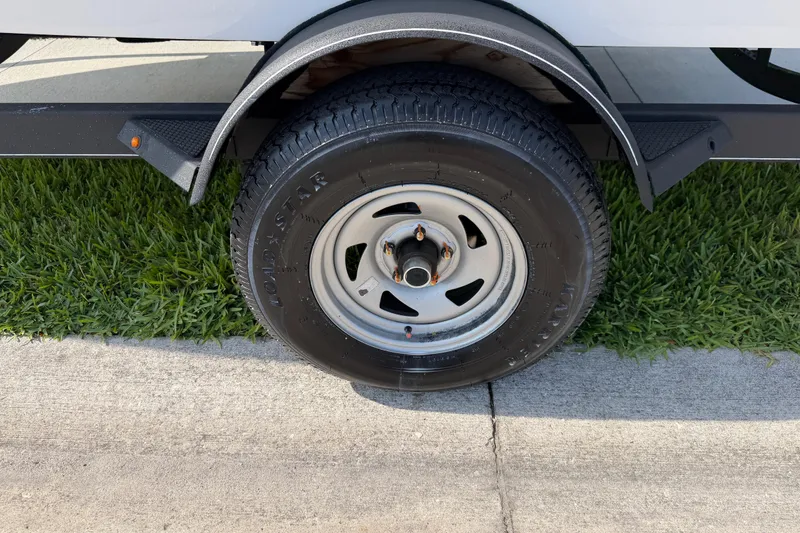 Slide: The Image of 2023 Tahoe T18 trailer wheel on grass and pavement. - 26