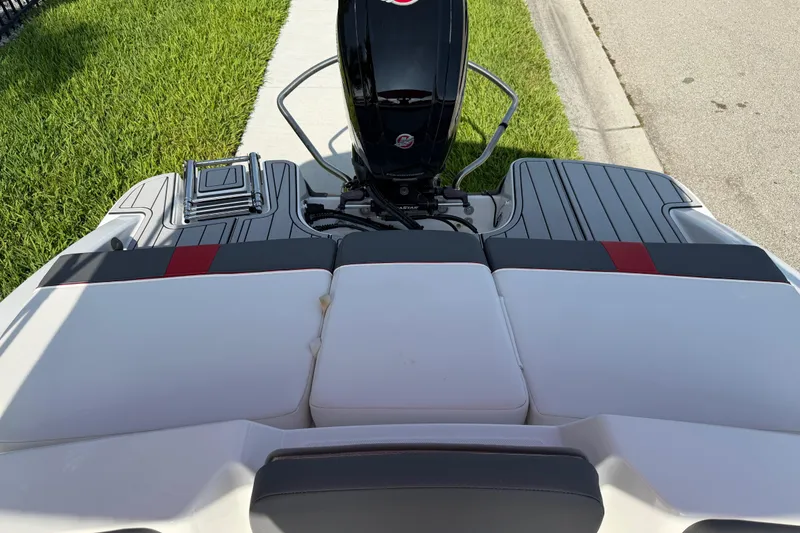 Slide: The Image of 2023 Tahoe T18 boat with cushioned seating and outboard motor, parked on grass. - 75