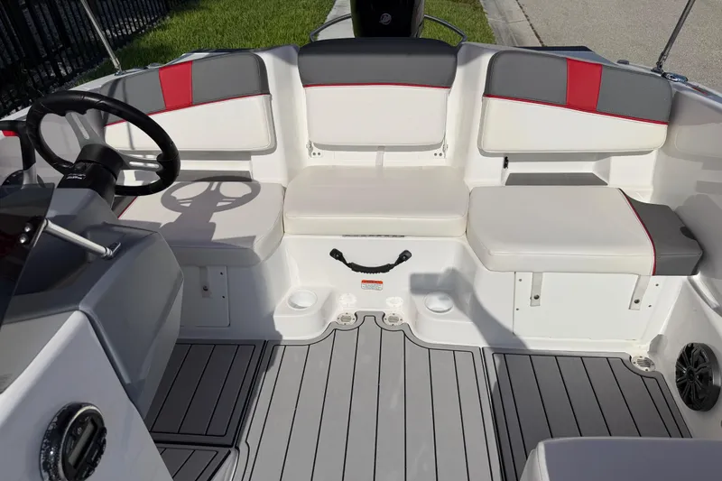 Slide: The Image of 2023 Tahoe T18 boat interior with gray and red seating, steering wheel, and deck flooring. - 76