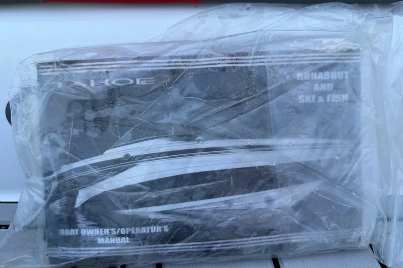 Slide: The Image of 2023 Tahoe T18 boat owner's manual in plastic wrap, featuring runabout and ski & fish details. - 87