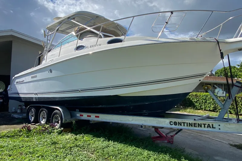Slide: The Image of 2002 Wellcraft 290 Coastal boat on trailer, parked outdoors under cloudy sky. - 13
