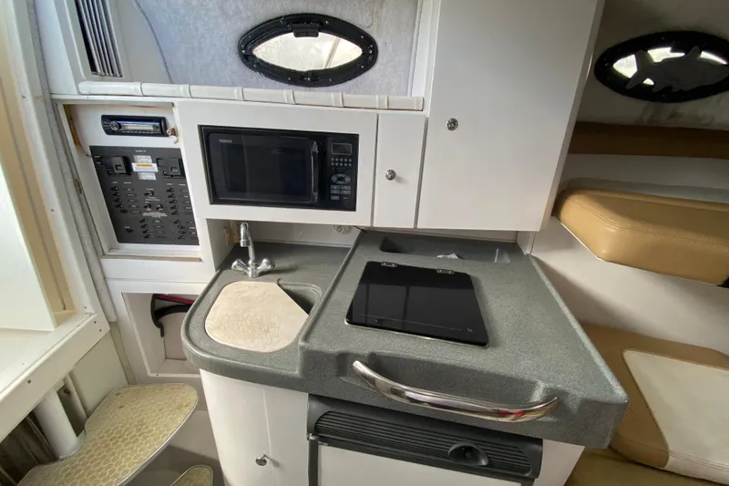 Slide: The Image of 2002 Wellcraft 290 Coastal boat interior with kitchenette, microwave, and seating area. - 34